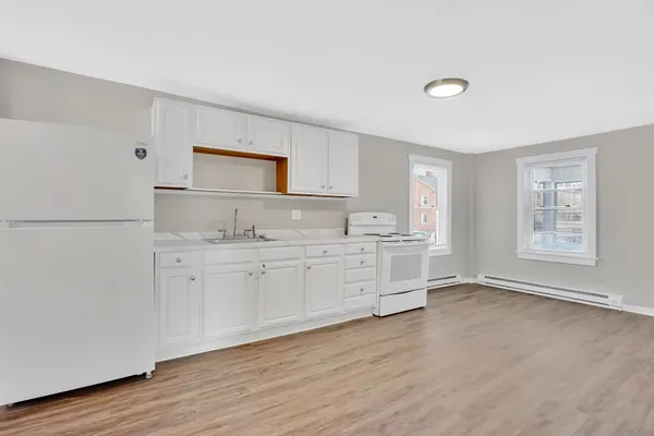a kitchen with granite countertop white cabinets and wooden floor