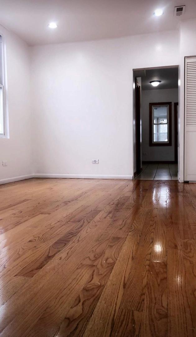 1828 North Pulaski Road, Unit 2 Chicago, IL 60639 - Photo 2 of 6 an empty room with wooden floor and fireplace