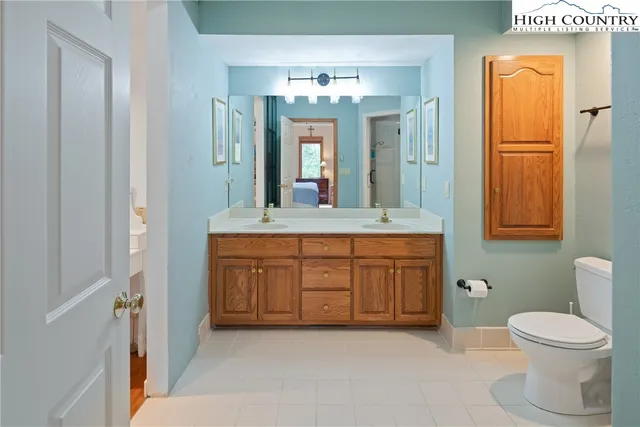 a spacious bathroom with a granite countertop sink a toilet a large mirror and shower