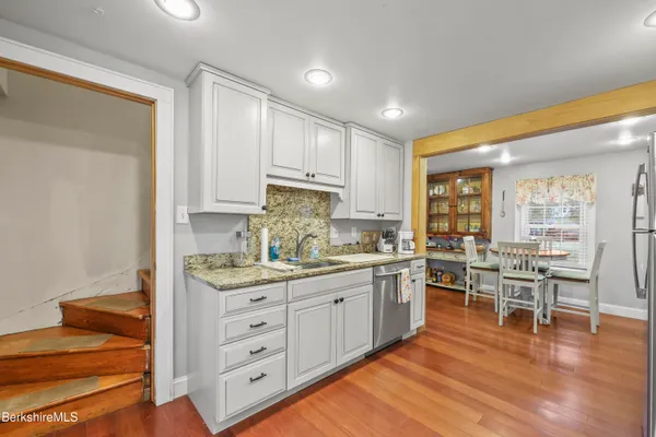 a kitchen with stainless steel appliances granite countertop a stove and white cabinets with wooden floor