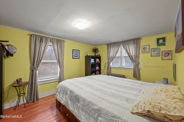a bedroom with a bed and a dresser with wooden floor