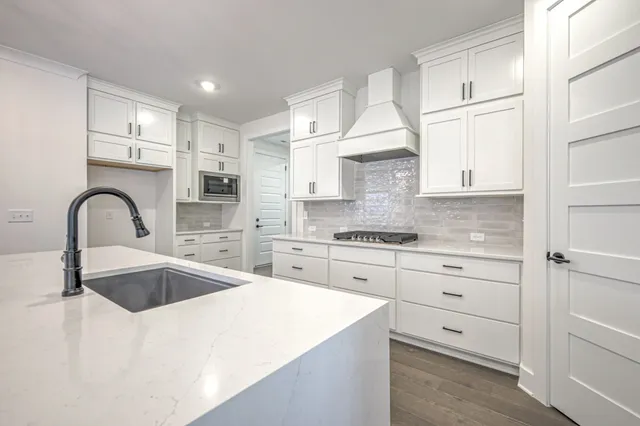 a kitchen with granite countertop white cabinets and stainless steel appliances