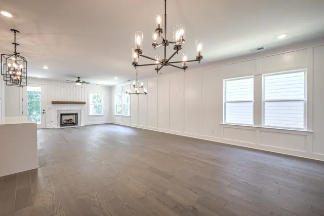 a view of a livingroom with a fireplace a ceiling fan and windows