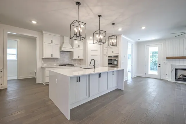 a large kitchen with stainless steel appliances kitchen island granite countertop a stove a sink a refrigerator and a wooden floor