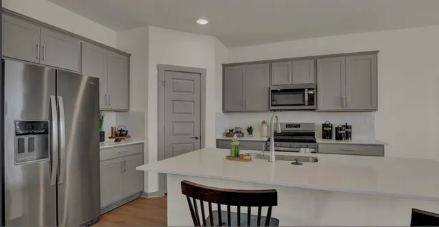 a kitchen with stainless steel appliances a refrigerator a sink a stove a table and chairs