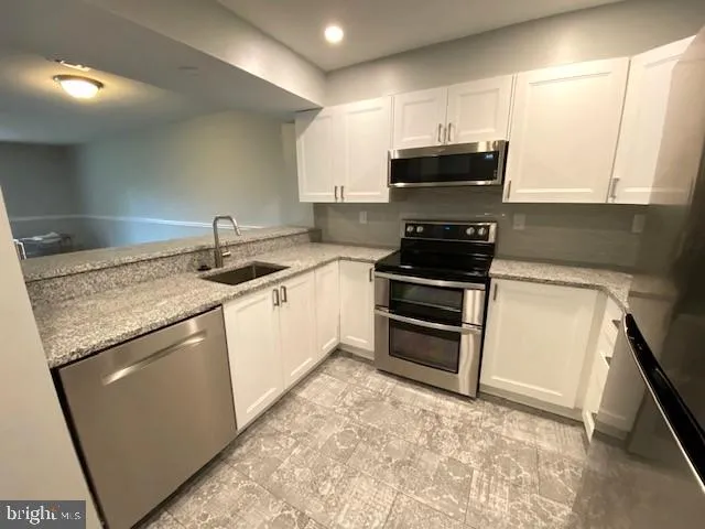 a kitchen with kitchen island granite countertop a stove sink and microwave