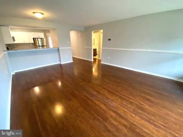 a view of a big room with wooden floor and a kitchen