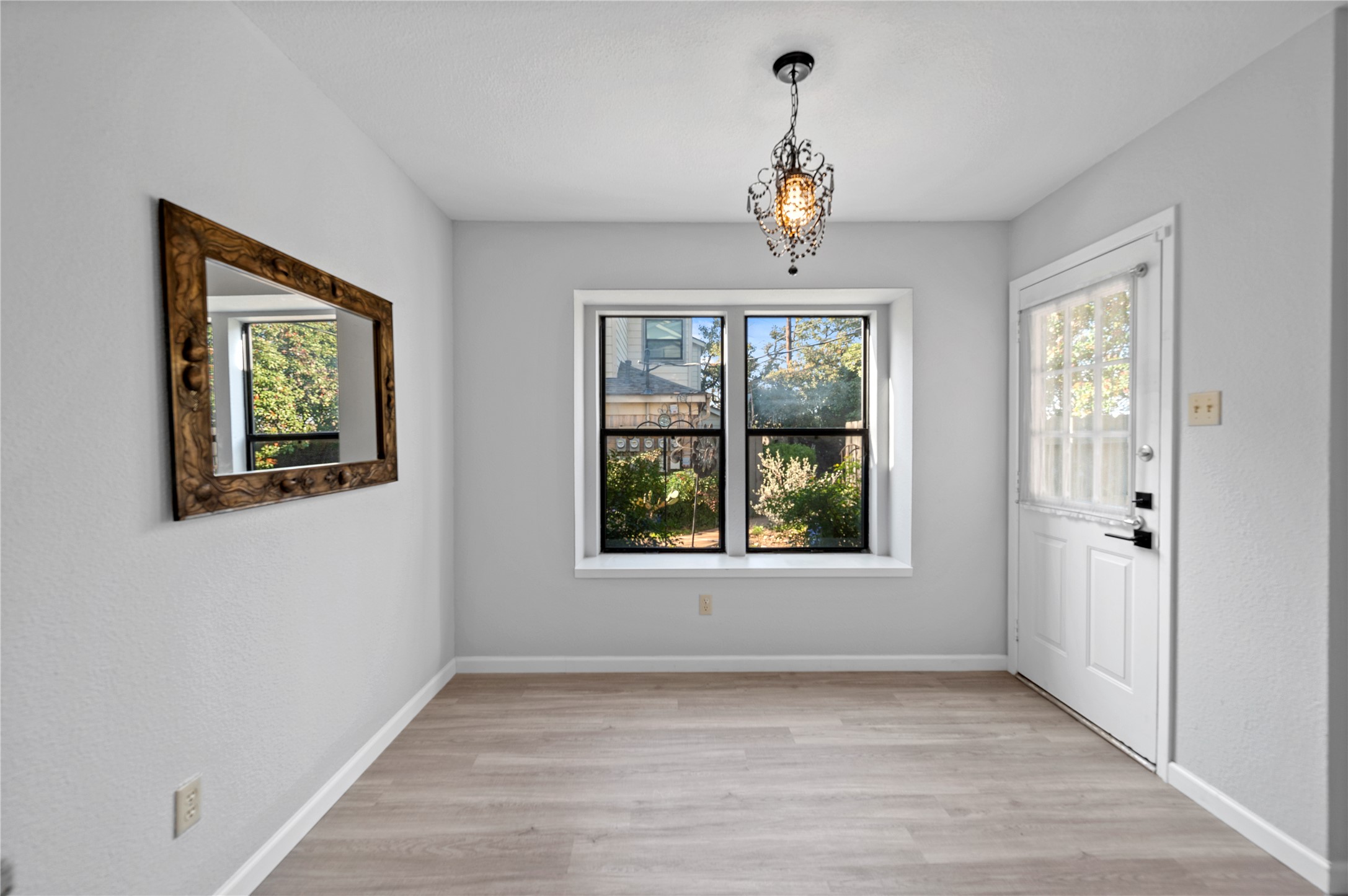 11301 Jollyville Road, Unit B3 Austin, TX 78759 - Photo 7 of 23 Unfurnished dining area with light wood-style floors, a chandelier, and a textured wall