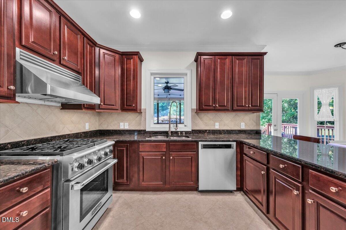 2908 Oak Bridge Drive Raleigh, NC 27610 - Photo 14 of 47 a kitchen with stainless steel appliances granite countertop wooden cabinets stove top oven and sink