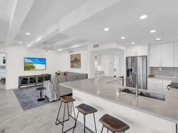 a living room with furniture a large window and stainless steel appliances