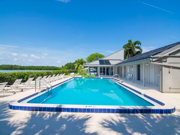 a view of a swimming pool with lawn chairs and plants