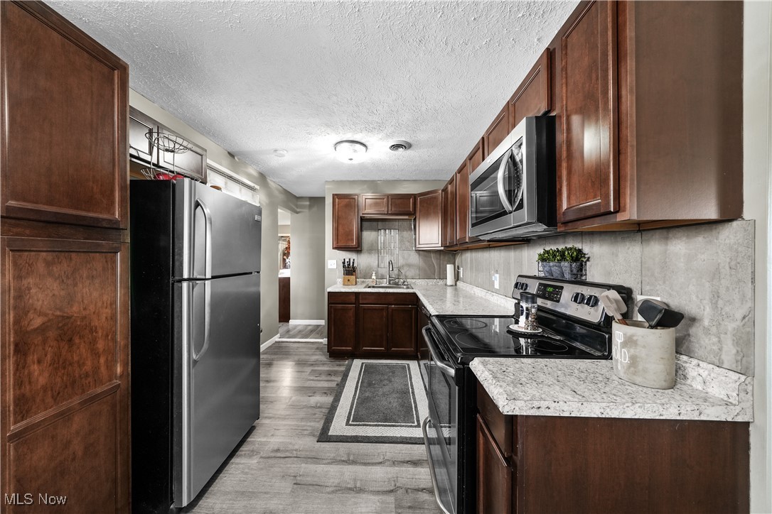 1503 Old Forge Road Kent, OH 44240 - Photo 6 of 38 Kitchen featuring dark brown cabinets, stainless steel appliances, hardwood / wood-style flooring, and sink