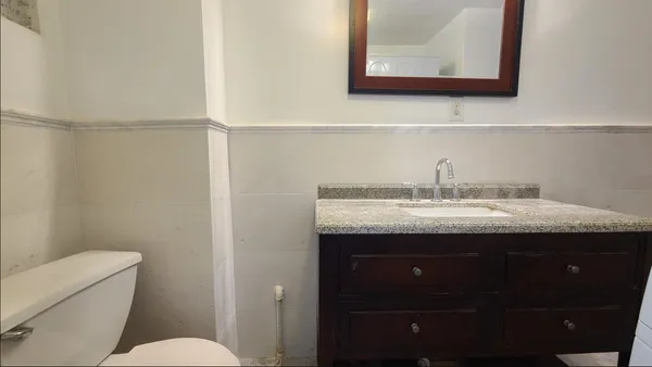 a bathroom with a granite countertop sink a toilet and a mirror