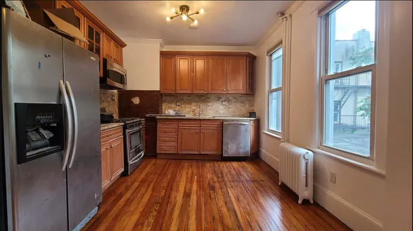 a kitchen with stainless steel appliances a refrigerator sink and wooden floor