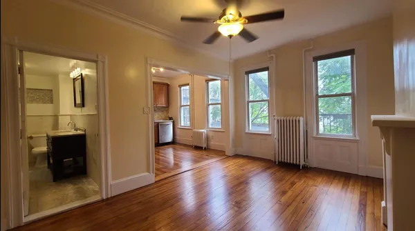 a view of an empty room with a window and wooden floor