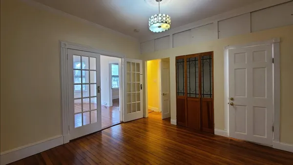 an empty room with wooden floor cabinet and windows