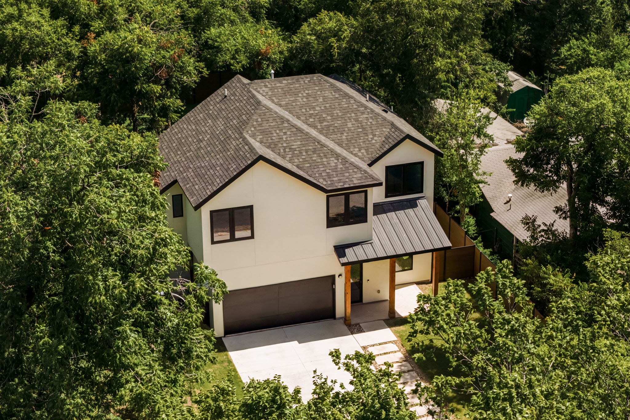3210 Thompson Street Austin, TX 78702 - Photo 35 of 39 A modern facade with a striking dark roof and warm wood accents, framed by lush greenery.