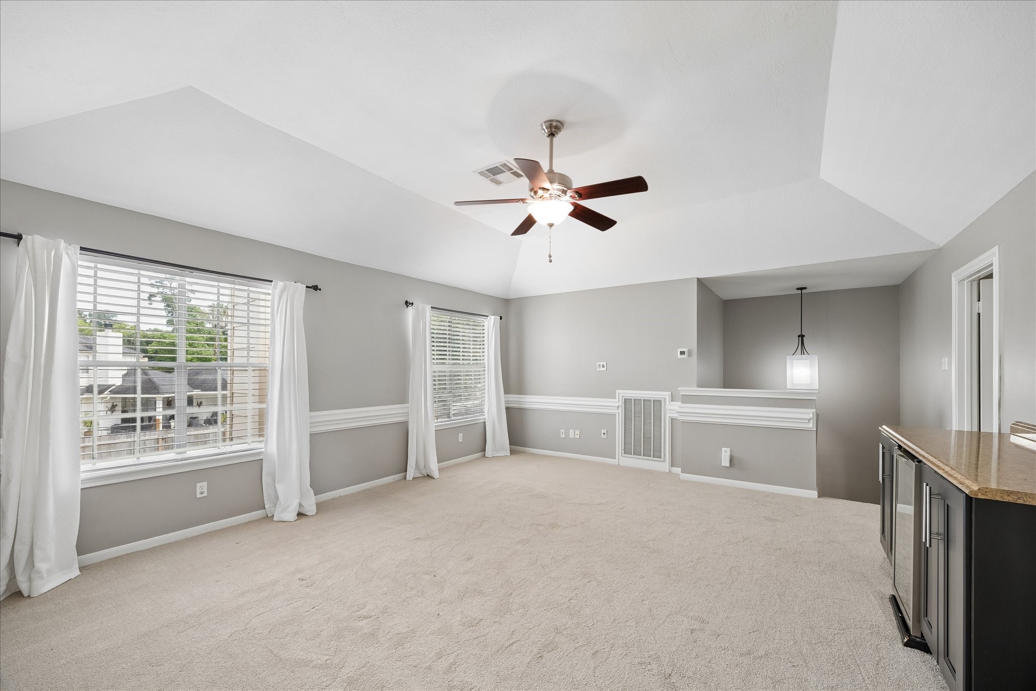 7915 Huddersfield Court Spring, TX 77379 - Photo 31 of 37 Alternate view of the spacious second-floor game room with vaulted ceiling, large windows, built-in bar area, and room for media, play, or entertaining. The stairs straight ahead lead to the family room downstairs