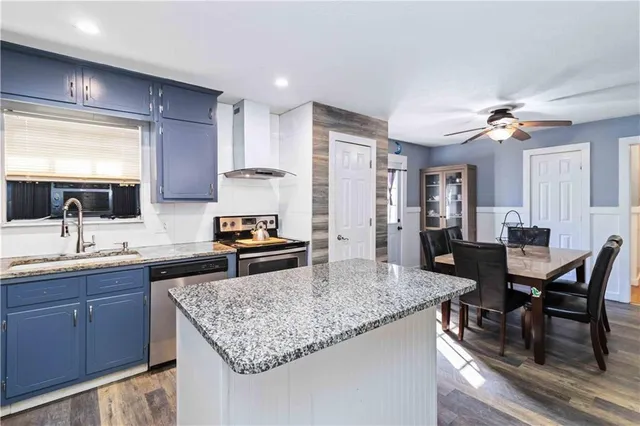 a kitchen with granite countertop kitchen island stainless steel appliances a sink stove and table