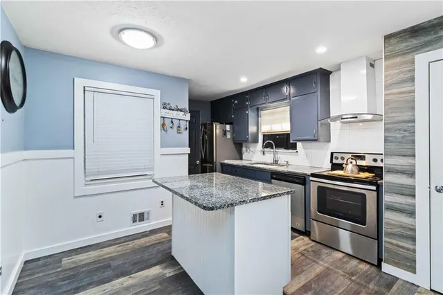 a kitchen with granite countertop a sink stove and cabinets