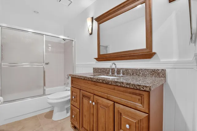 a bathroom with a granite countertop sink toilet and shower