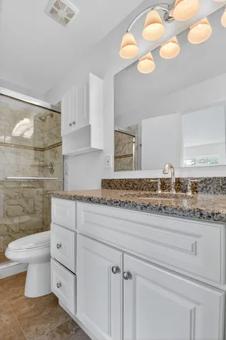 a bathroom with a granite countertop toilet sink and mirror