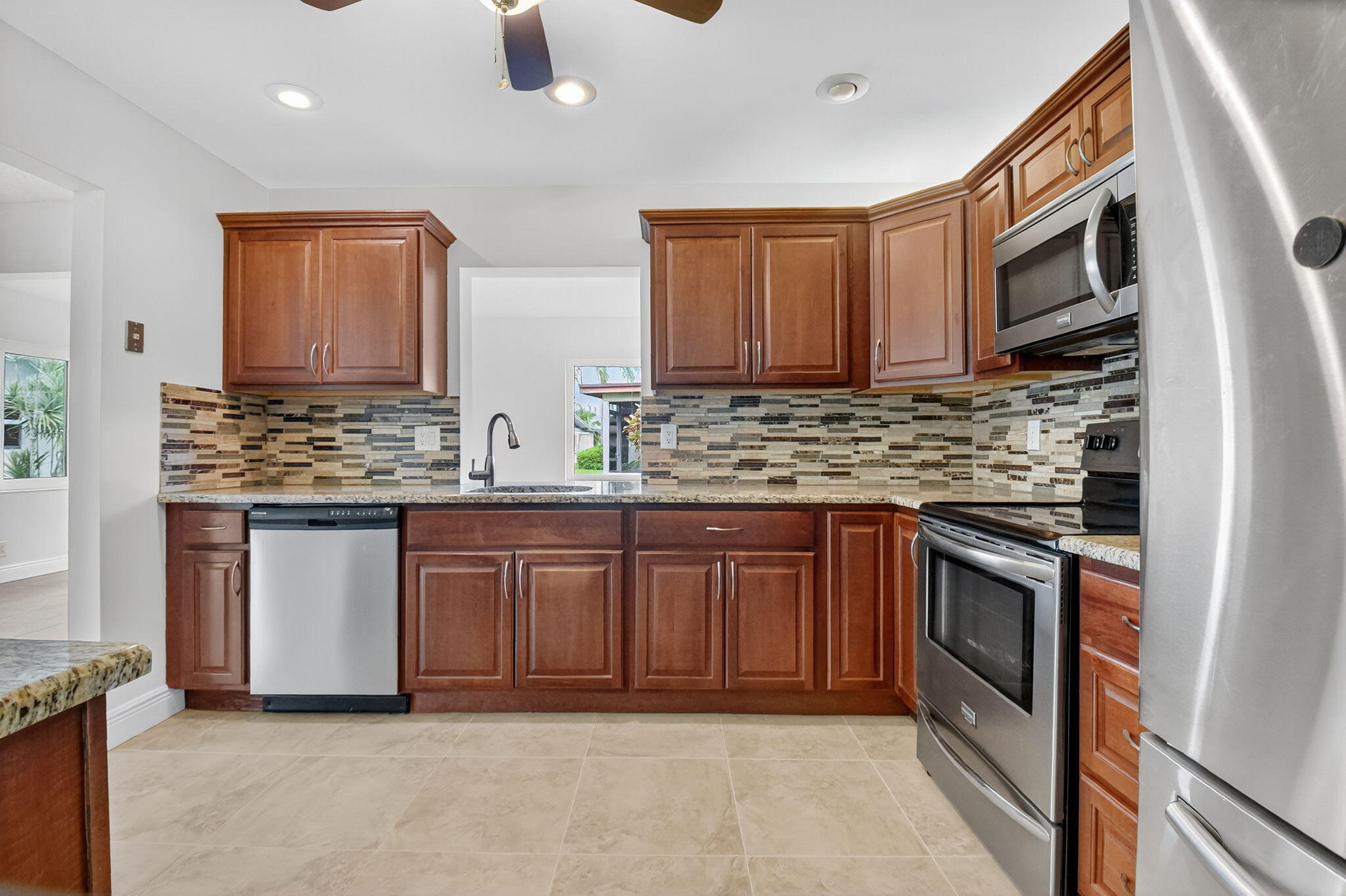 6096 Dusenburg Road Delray Beach, FL 33484 - Photo 6 of 28 a kitchen with stainless steel appliances granite countertop a stove microwave and sink