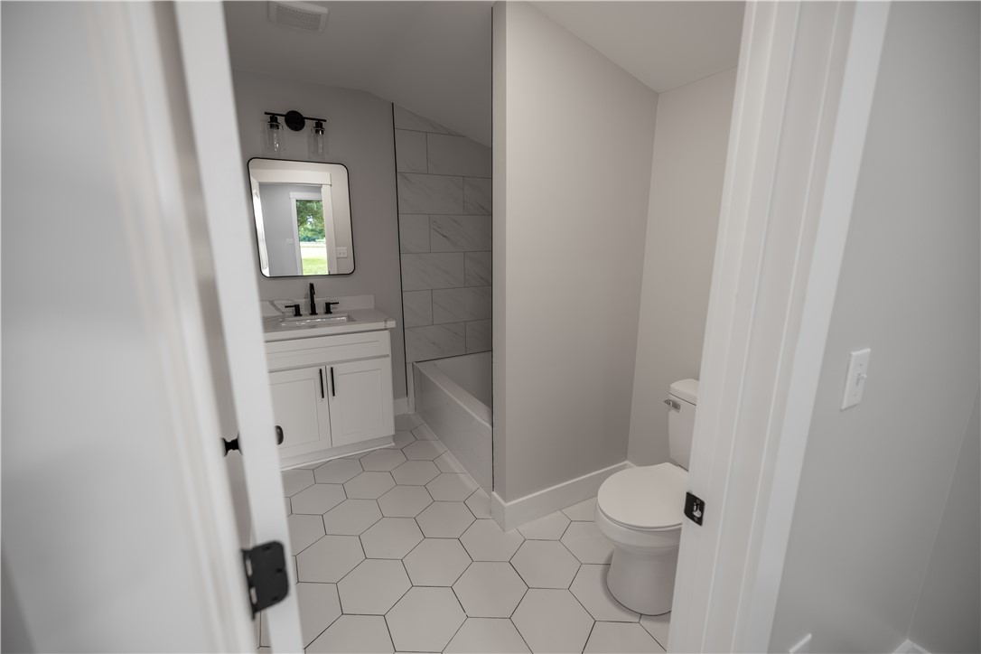 2817 Broadway Lake Road Anderson, SC 29621 - Photo 29 of 41 A pristine bathroom features a crisp white vanity, a tub with tiled surround, and hexagonal floor tiles.
