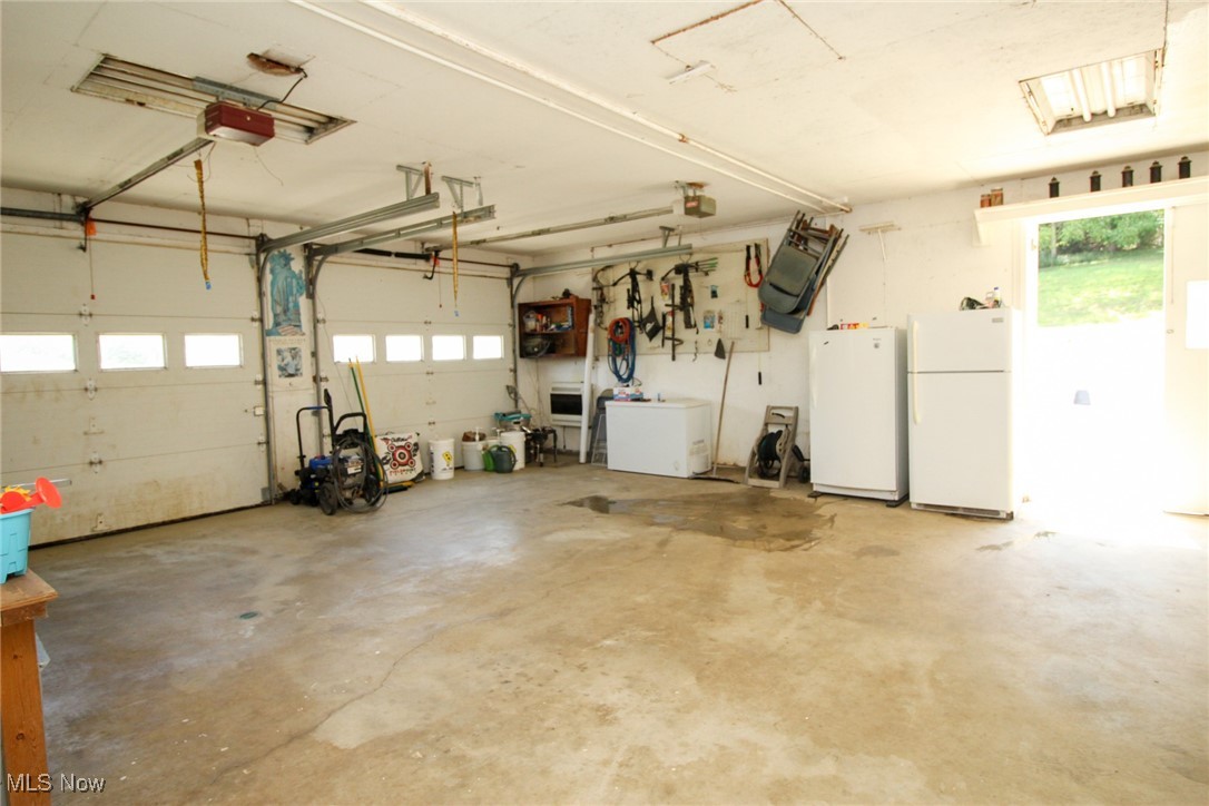 1798 Campbell Road Southwest New Philadelphia, OH 44663 - Photo 7 of 50 Garage featuring a garage door opener and white fridge