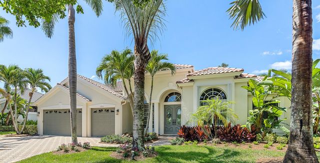 a yellow and white house with a palm tree in front of it