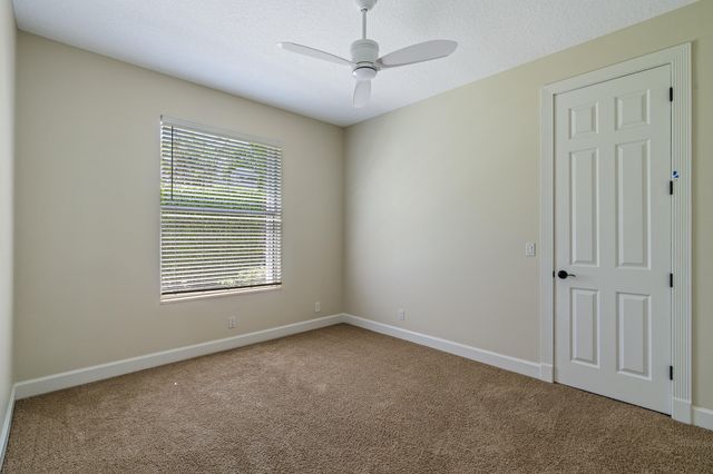 an empty room with wooden floor windows and a chandelier