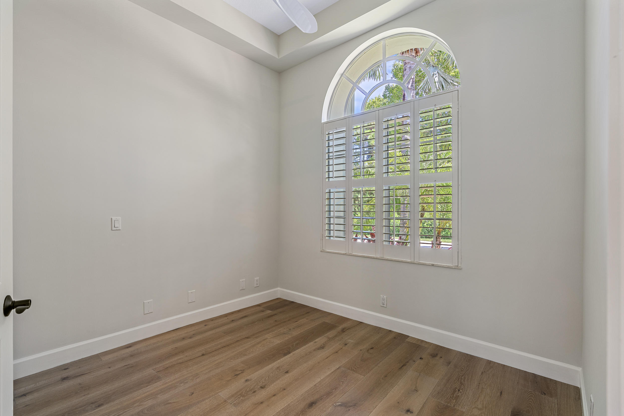19866 Loxahatchee Pointe Drive Jupiter, FL 33458 - Photo 36 of 43 an empty room with wooden floor windows and a chandelier