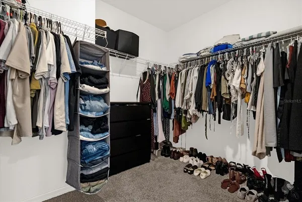 a view of walk in closet with clothes and shoes