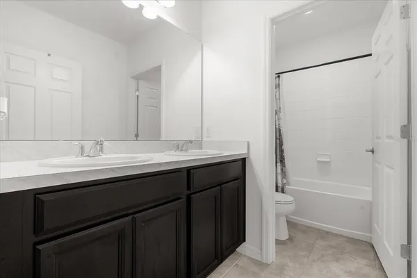a bathroom with a double vanity sink toilet mirror and bathtub