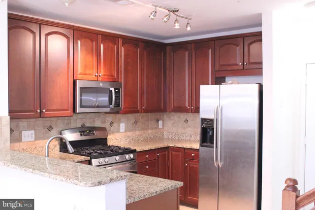 a kitchen with stainless steel appliances granite countertop a refrigerator a stove top oven a sink and dishwasher