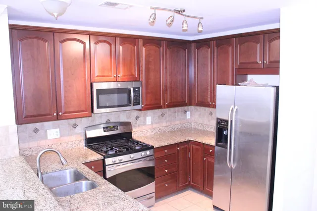 a kitchen with granite countertop wooden cabinets and stainless steel appliances