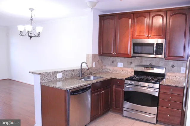 a kitchen with granite countertop a sink stainless steel appliances and cabinets