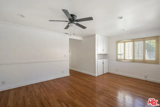 an empty room with wooden floor fan and windows