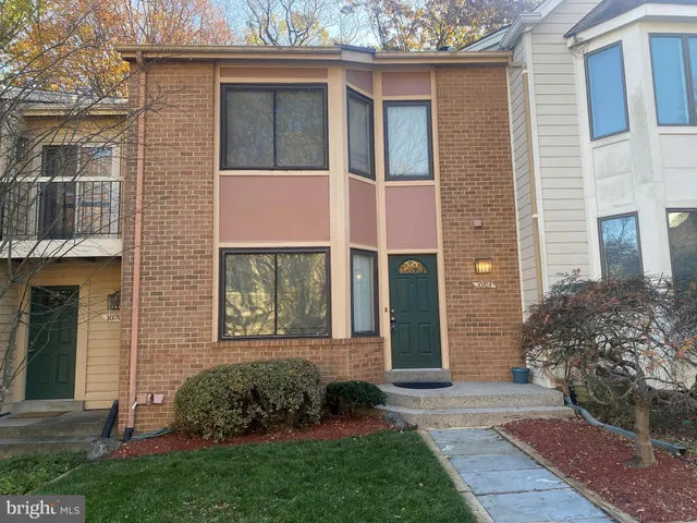 a view of a brick house with many windows and plants