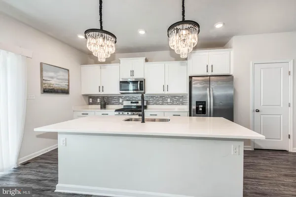 a large kitchen with kitchen island a stove a sink dishwasher a dining table and chairs with wooden floor