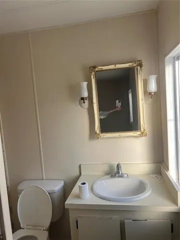 a bathroom with a toilet sink vanity and mirror
