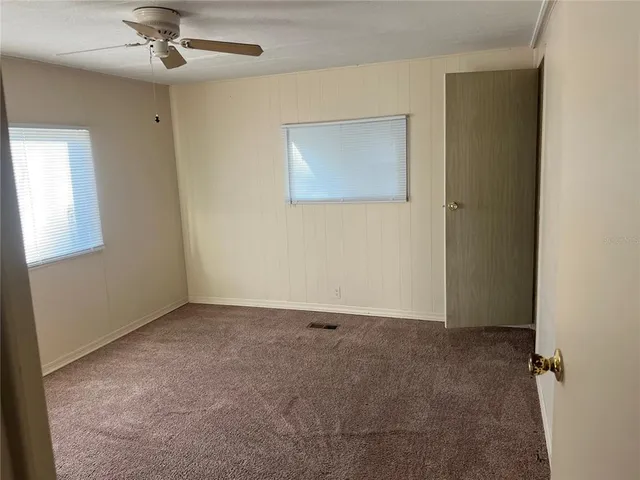 an empty room with a ceiling fan and a window