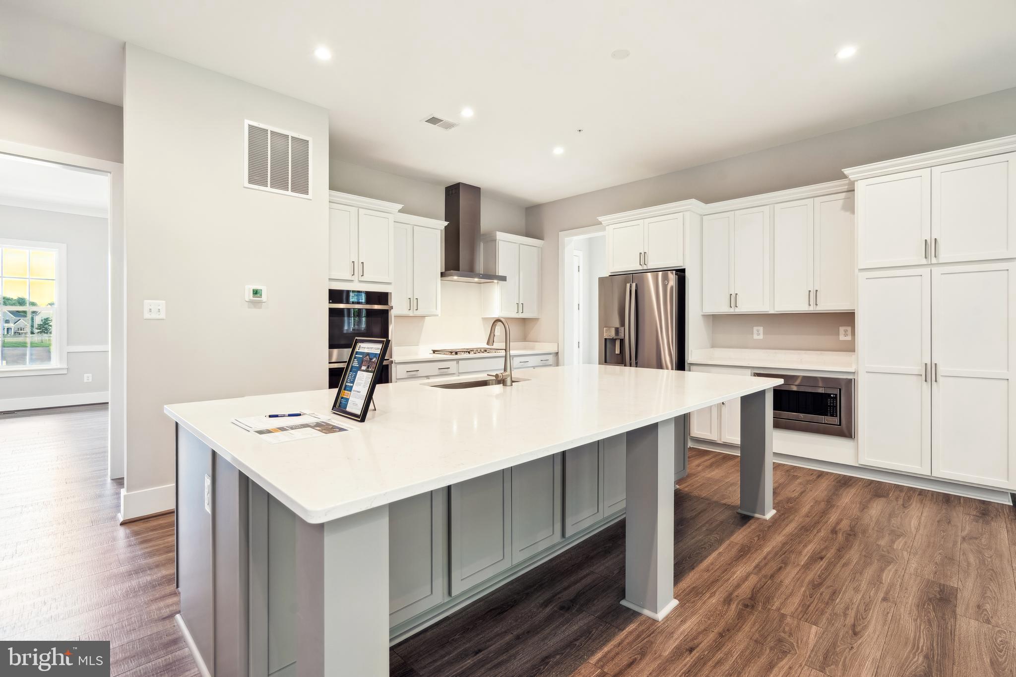 3906 Diplomat Avenue Bowie, MD 20721 - Photo 12 of 47 a kitchen with a sink a stove a refrigerator and white cabinets with wooden floor