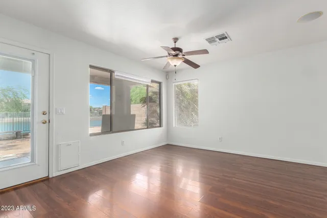 an empty room with wooden floor and windows