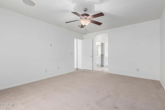 an empty room with chandelier fan and view of ceiling fan