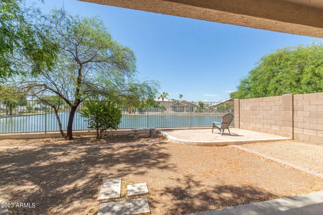 a view of a yard with a house and trees in the background