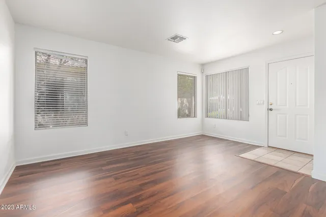 an empty room with wooden floor and windows