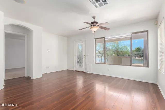 a view of an empty room with wooden floor and a window