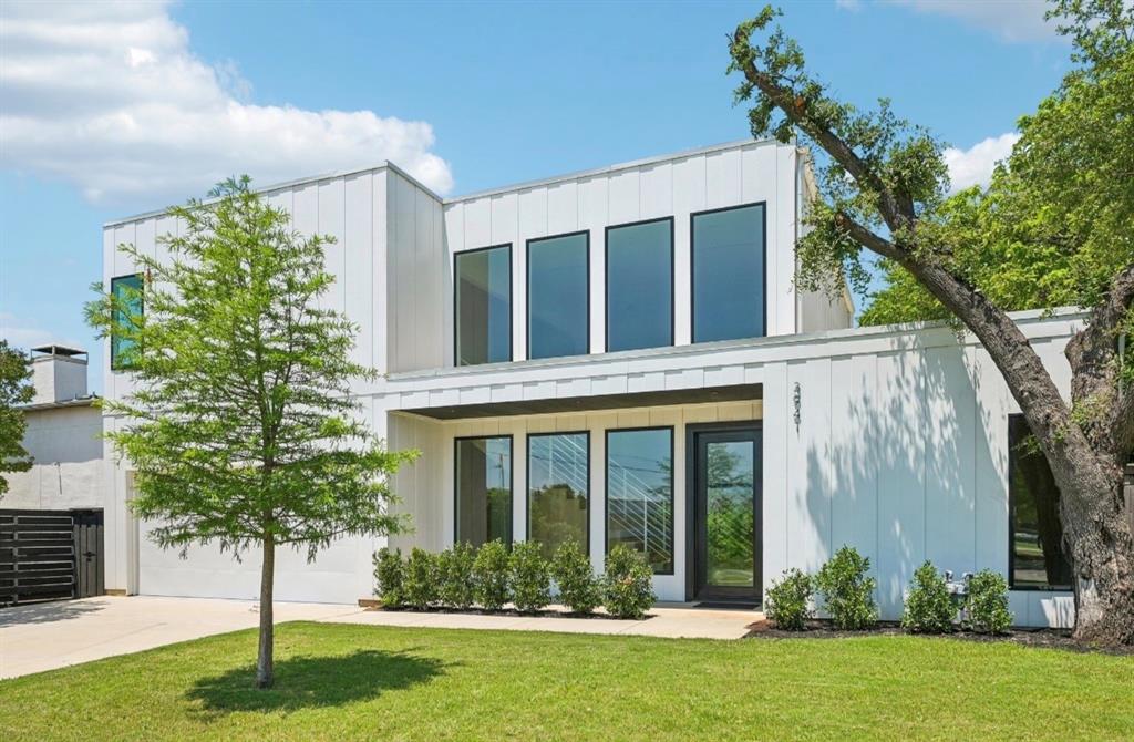 Modern architectural facade featuring white vertical siding, flat rooflines, and a black framed glass entry door