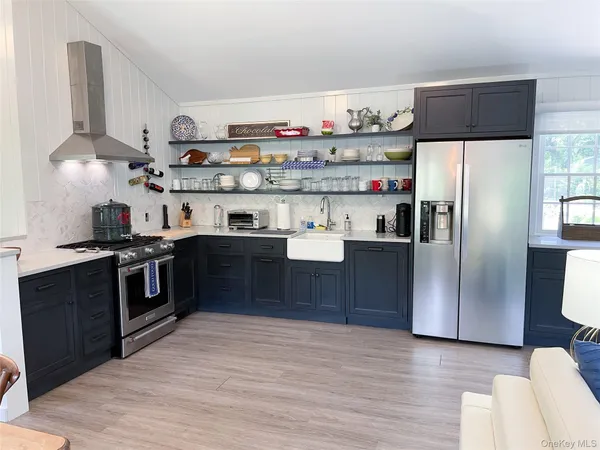 a kitchen with stainless steel appliances granite countertop a refrigerator and a wooden floors